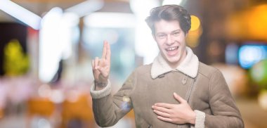 Genç yakışıklı adam giyen kış ceket izole üzerinde arka plan Swearing göğüs ve bir sadakat sözü yemin yapma parmaklar, el ile