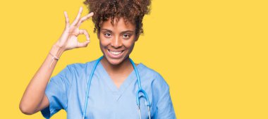 Gülümseyen izole arka plan üzerinde genç Afro-Amerikan doktor kadın el ve parmaklar ok işaretiyle yapıyor olumlu. Başarılı ifade.