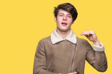 Genç yakışıklı adam büyük ve büyük boy işareti gösteren elleri ile izole arka plan gesturing üzerinde kış ceket giyen, sembol ölçmek. Kameraya bakarak gülümsüyor. Ölçme kavramı.