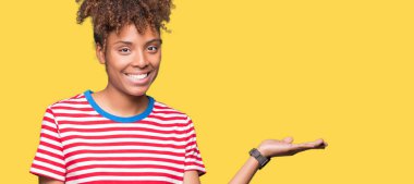 Neşeli sunulması ve kameraya bakarak avucunun ile işaret gülümseyen izole arka plan güzel genç Afro-Amerikan kadın.