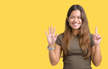 İzole arka plan üzerinde genç güzel esmer kadın gösteren ve parmak numarası altı ile işaret kadar güven ve mutlu gülümseyen.