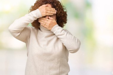 Boğazlı kazak ve gözlük izole arka plan kaplaması gözler ve ağız el ile üzerinden giyen güzel orta ager üst düzey kadın şaşırttı ve şok. Duygu gizleme