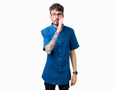 Genç yakışıklı adam gözlük izole arka plan üzerinde kötü amaçlı konuşma konuşma fısıldayan gizli söylenti söylüyor dudaklarından el