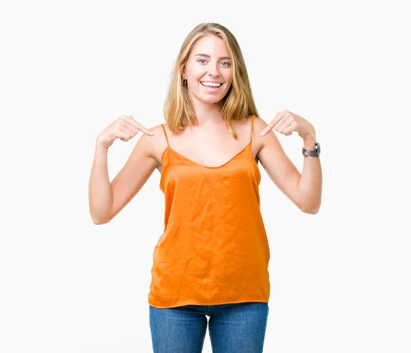 美しい若い女性の顔に笑顔と自信を持って 誇りと幸せな指で自分を指している孤立した背景にオレンジ色のシャツを着て — ストック写真