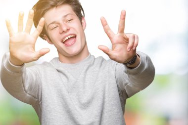 Gösterilen arka plan üzerinde sweatshirt giyen genç yakışıklı sportif adam izole ve parmakları ile işaret kendinden emin ve mutlu gülümseyerek süre 8 numaralı.