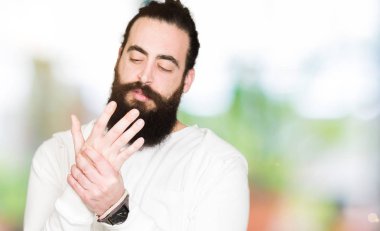 Genç hipster uzun saçlı adam ve elleri ve parmakları, artrit inflamasyon giyen sportif kazak acı acı sakal