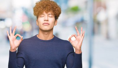 Saç relax afro genç yakışıklı adamla ve gülümseyen gözlerle parmak ile meditasyon jest yapıyor kapalı. Yoga kavramı.