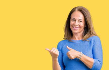 Orta yaş üzerinde kış kazak giyen güzel kadın izole arka plan emin gülümseyen arkasından el ve kadar başparmak ile işaret