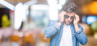 Genç yakışıklı adam giyen güneş gözlüğü bitti çünkü arka plan baş baş ağrısı için el ile izole stres. Migren muzdarip.