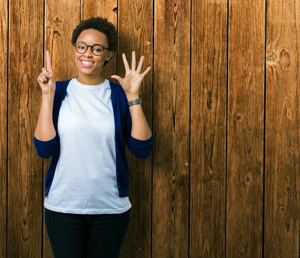 Genç güzel Afrikalı-Amerikalı kadın gözlük gösterilen ve parmakları ile işaret izole arka plan üzerinde kendinden emin ve mutlu gülümseyerek süre 6 numara.
