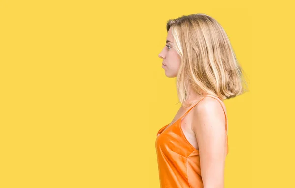 美しい若い女性側を分離の背景にオレンジ色のシャツを着てリラックス自信を持って笑顔で自然の顔を持つプロファイル ポーズ — ストック写真