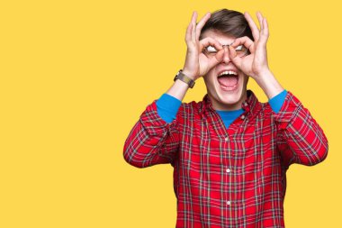 Dilini, parmaklarının arasından baktığını yapışmasını dürbün gibi ok jest yapıyor izole arka plan üzerinde gözlük takan yakışıklı delikanlı. Deli ifade.