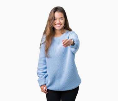 Tebrik ve konuksever dost sunan karşılıklı gülümseyen izole arka plan üzerinde mavi kış kazak giyen genç güzel esmer kadın. Başarılı iş.