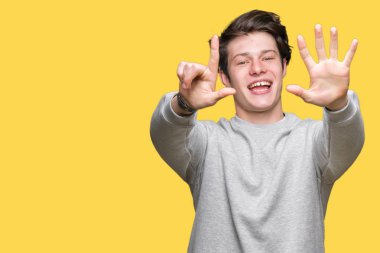 Genç yakışıklı sportif adam izole arka plan üzerinde sweatshirt giyen gösteren ve emin ve mutlu gülümserken parmakları ile yedi numara işaret.