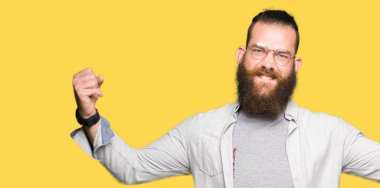 Gözlük giyen genç sarışın adam gururlu gülümseyen silah kasları gösteren. Fitness konsepti.