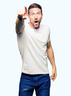Devam et, Casual beyaz t-shirt işaret parmağınızla sürpriz giyen yakışıklı adam ağız açık ifade, önünde bir şey hayret