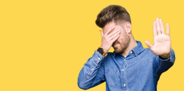 Genç yakışıklı sarışın adam rahat kot gömlek kapsayan gözleri elleriyle giyen ve stop jest ile acı ve korku ifadesi. Utandım ve negatif kavramı.