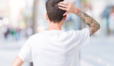 İzole arka plan geriye düşünme hakkında şüphe kafasına el ile üzerine beyaz t-shirt giyen genç yakışıklı adam