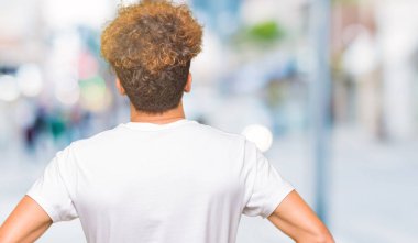 Geriye doğru uzakta silah ile vücut üzerinde seyir ayakta casual beyaz t-shirt giyen afro saçlı genç yakışıklı adam