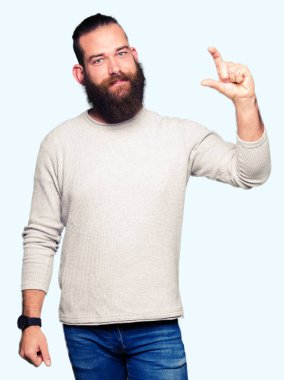 Genç sarışın adam rahat kazak giyen gülümseyen ve boyutu işi el ile kendinden emin eller parmakları ile seyir ve fotoğraf makinesi oturum açın. Ölçü kavramı.