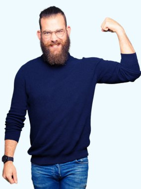 Genç Sarışın giyen gözlük ve balıkçı yaka kazak güçlü kişi gösteren kol kas, kendinden emin ve güç gurur adam