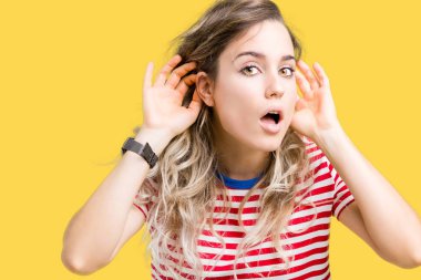 Güzel sarışın genç kadın her iki kulak jest, dedikodu için meraklı ellerde dinliyoruz izole arka plan üzerinde. İşitme sorunu, sağır