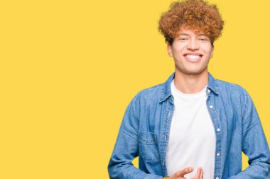 Afro saçlı kot giyen genç yakışıklı adam ceket el ele tutusun ve rahat ve neşeli gülümseyen parmak çarpı işareti. Başarı ve iyimser