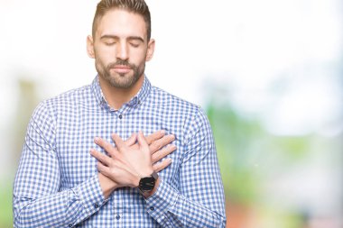 Yakışıklı delikanlı ile gülümseyen izole arka plan üzerinde kapalı gözler ve yüzünde minnettar jest ile göğüs üzerinde eller. Sağlık kavramı.