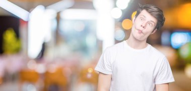 İzole arka plan yapma balık yüzüne dudaklı, çılgın ve komik bir jest Casual beyaz t-shirt giyen genç yakışıklı adam. Komik ifade.