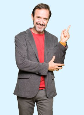 Kameraya bakarak yan el ve parmak ile işaret orta yaş yakışıklı iş adamı yüzünde kocaman bir gülümseme ile.