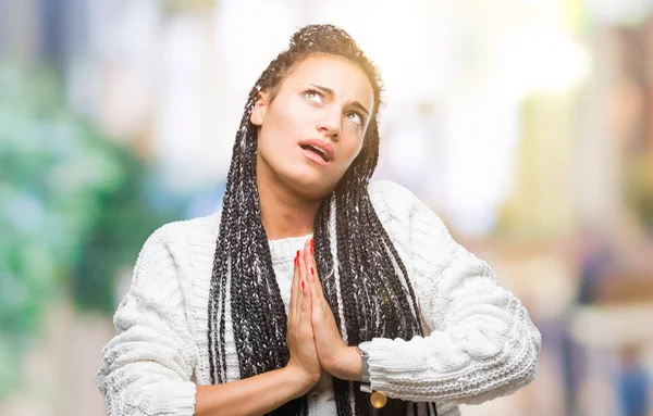 Young braided hair african american girl wearing sweater over isolated background begging and praying with hands together with hope expression on face very emotional and worried. Asking for forgiveness. Religion concept.