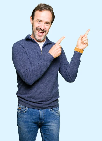 Gülümseyen ve iki elleri ve parmakları ile tarafına işaret kamera bakarak bir kazak giyen orta yaş yakışıklı adam.