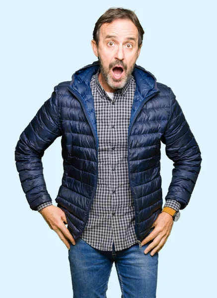 Orta yaş yakışıklı adam korkuyor ve şok sürpriz ifade, korku ve heyecan yüz ile bir kış palto giyiyor.