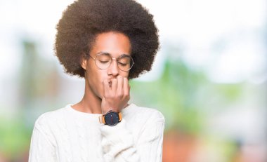 Afrikalı-Amerikalı genç afro saçlı gözlüklü stresli ve gergin elle çivi ısırma ağzına bakıyor. Anksiyete sorunu.