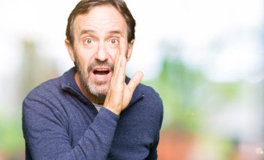 Orta yaş yakışıklı adam kazak giyiyor el gizli söylenti söylüyor ağızdan kötü amaçlı konuşma konuşma fısıldayan