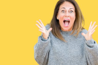 Üzerinde kış kazak giyen güzel orta yaş kadın deli kutluyor arka plan izole ve başarı için kaldırdı kollarını açarak hayrete ve heyecanlı çığlık gözleri açık. Kazanan kavramı