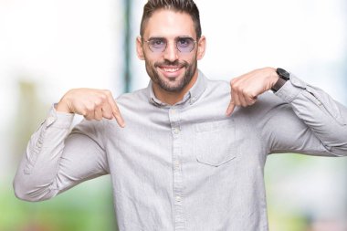 Yakışıklı delikanlı yüzünde gülümseme ile kendinden emin görünüyorsun, kendini gururlu ve mutlu parmakları ile işaret izole arka plan üzerinde güneş gözlüğü takıyor.