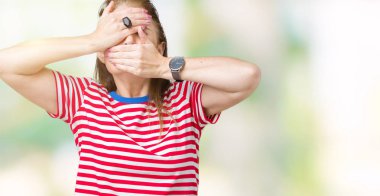 Orta yaş Olgun kadın izole arka plan kaplaması gözler ve ağız el ile üzerinden rahat t-shirt giyen şaşırttı ve şok. Duygu gizleme