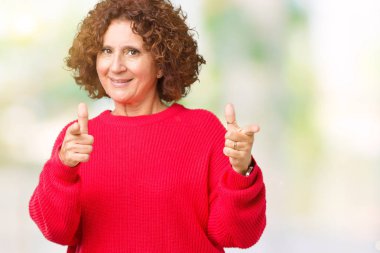 Güzel orta ager üst düzey kadın kırmızı kış kazak için fotoğraf makinesi ile mutlu ve komik yüz parmakları işaret izole arka plan üzerinde. İyi enerji ve vibes.