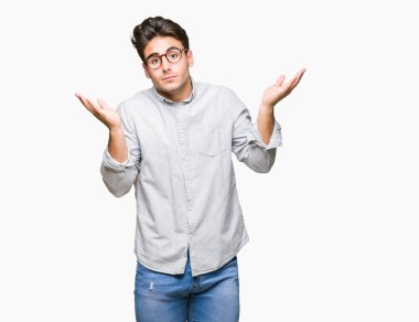 İzole arka plan clueless ve şaşkın bir ifadeyle kollar ve eller kaldırdı üzerinde gözlük takan yakışıklı delikanlı. Şüphe kavramı.
