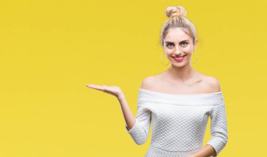 Neşeli sunulması ve kameraya bakarak avucunun ile işaret gülümseyen izole arka plan genç güzel sarışın ve mavi gözlü kadın.