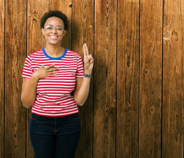 Güzel genç Afro-Amerikan kadın gözlük izole üzerinden Swearing göğüs ve bir sadakat sözü yemin yapma parmaklar, el ile arka plan