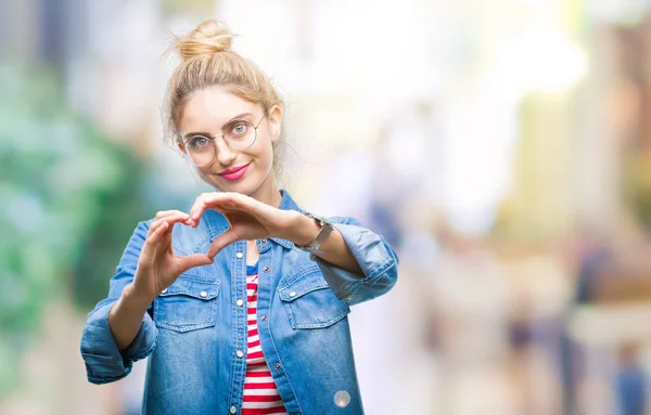 年轻美丽的金发女子戴着眼镜在孤独的背景微笑在爱显示心脏符号和形状用手 浪漫概念 — 图库照片