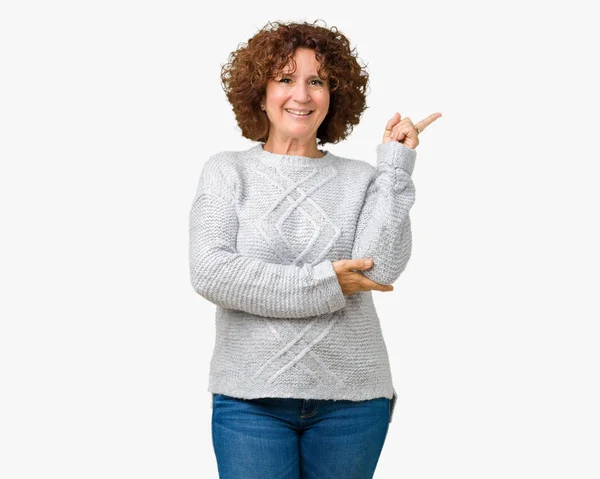 美丽的中间年龄的老年妇女穿着冬季毛衣在孤立的背景与一个很大的微笑在脸上 用手和手指指着一边看着镜头 — 图库照片