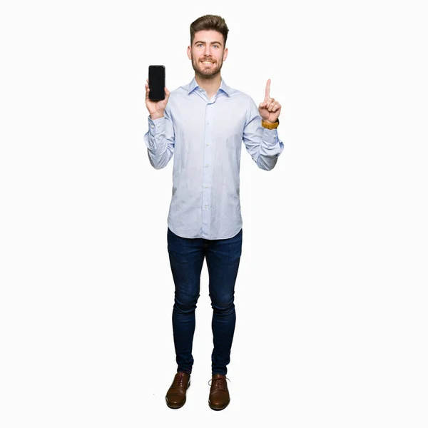Junger Gutaussehender Mann Zeigt Smartphone Bildschirm Überrascht Mit Einer Idee — Stockfoto