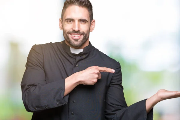 年轻的基督教牧师在孤立的背景惊讶和微笑的镜头 而提出用手和手指指指点点 — 图库照片