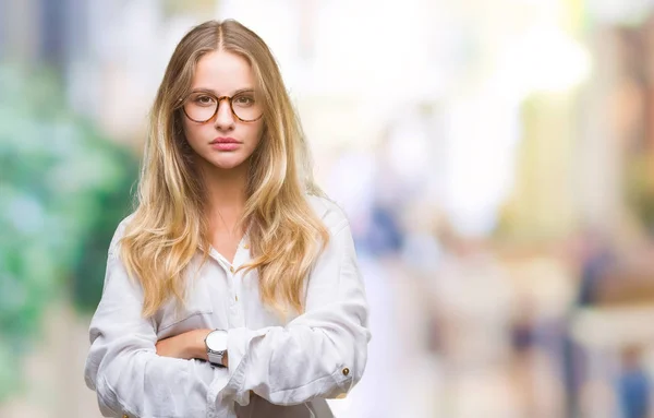 Young beautiful blonde business woman wearing glasses over isolated background skeptic and nervous, disapproving expression on face with crossed arms. Negative person.