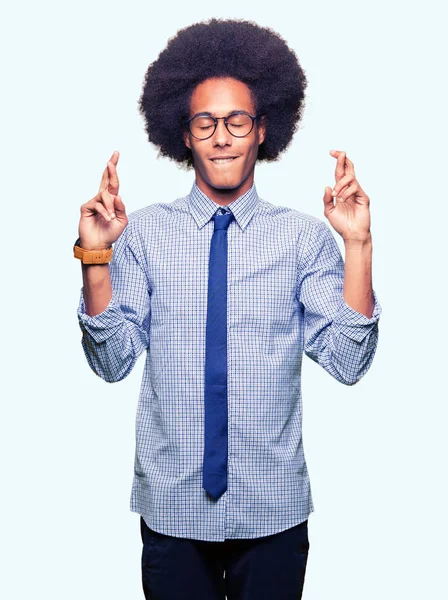 Молодой Африканский Бизнесмен Афроволосами Очках Улыбается Скрещивая Пальцы Надеждой Закрытыми — стоковое фото