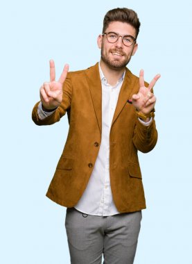 Zafer işareti yapıyor parmak gösterilen kamera seyir gülümseyen genç yakışıklı iş adam gözlük takıyorsun. İki numaralı.