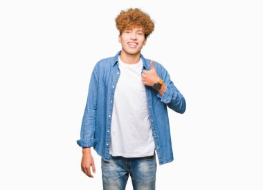 Yakışıklı genç afro saçlı hareketi el ile mutlu yaşasın yapıyor kot ceket giyiyor. Başarı gösteren kameraya bakarak ifade onaylama.